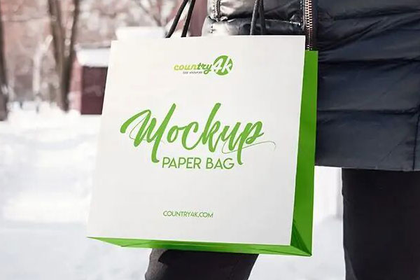 3/4 View of a Paper Bag Held Up by a Hand Mockup
