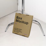 Cardboard Box Leaning Against Tripod Mockup