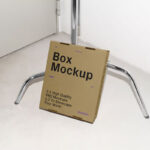 Cardboard Box Leaning Against Tripod Mockup