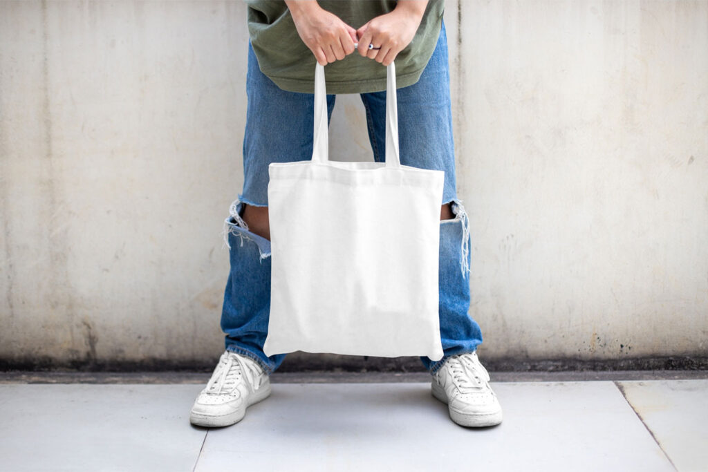 Casual Outdoor Man Holding Canvas Bag Mockup from Front View