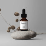 Cosmetic Bottle Mockup with Flower on Stone in Front View