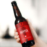 Female Hand Holding Glass Beer Bottle in the Air Mockup