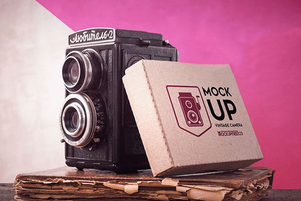 Flat Box Leaning onto Vintage Camera Mockup on Old Book