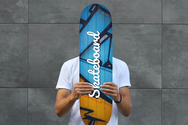 Front Sight of Man Holding Skateboard Mockup Against Wall