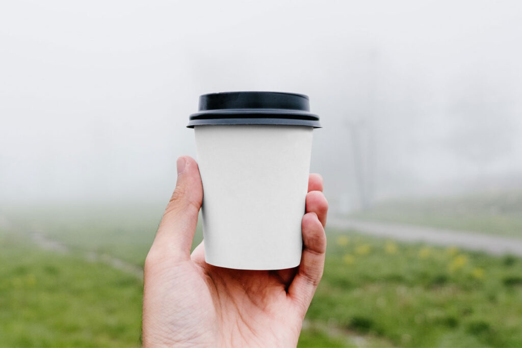 Front View of Hand Holding Coffee Cup Mockup in Park