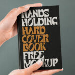 Front View of Hand Holding Hardcover Book Mockup