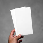 Front View of Hand Holding Vertical Leaflets Mockup