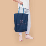 Half-Side View Cotton Tote Bag Featuring Someone Holding It Mockup