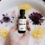 Hand Holding Food Essence Bottle with Milk and Flower Around Mockup