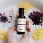 Hand Holding Food Essence Bottle with Milk and Flower Around Mockup