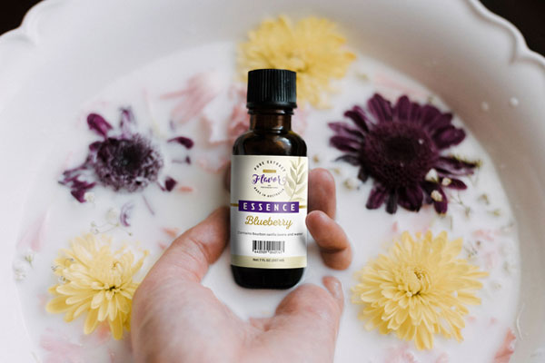 Hand Holding Food Essence Bottle with Milk and Flower Around Mockup