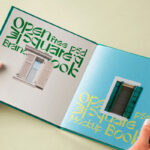 Hand Holding Hardcover Open Book Mockup in Perspective View