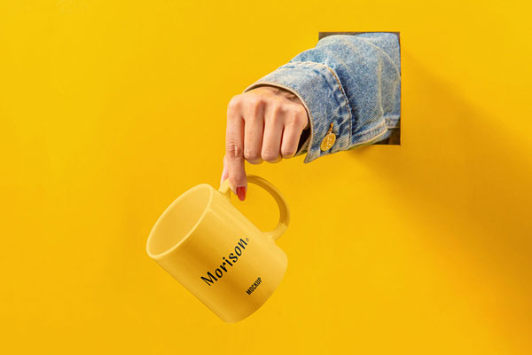 Hand Holding Mug out of Hole on the Wall Mockup