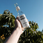 Handholding Glass Bottle Mockup in Nature