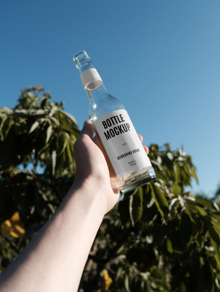 Handholding Glass Bottle Mockup in Nature