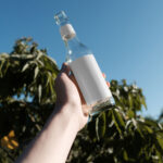 Handholding Glass Bottle Mockup in Nature