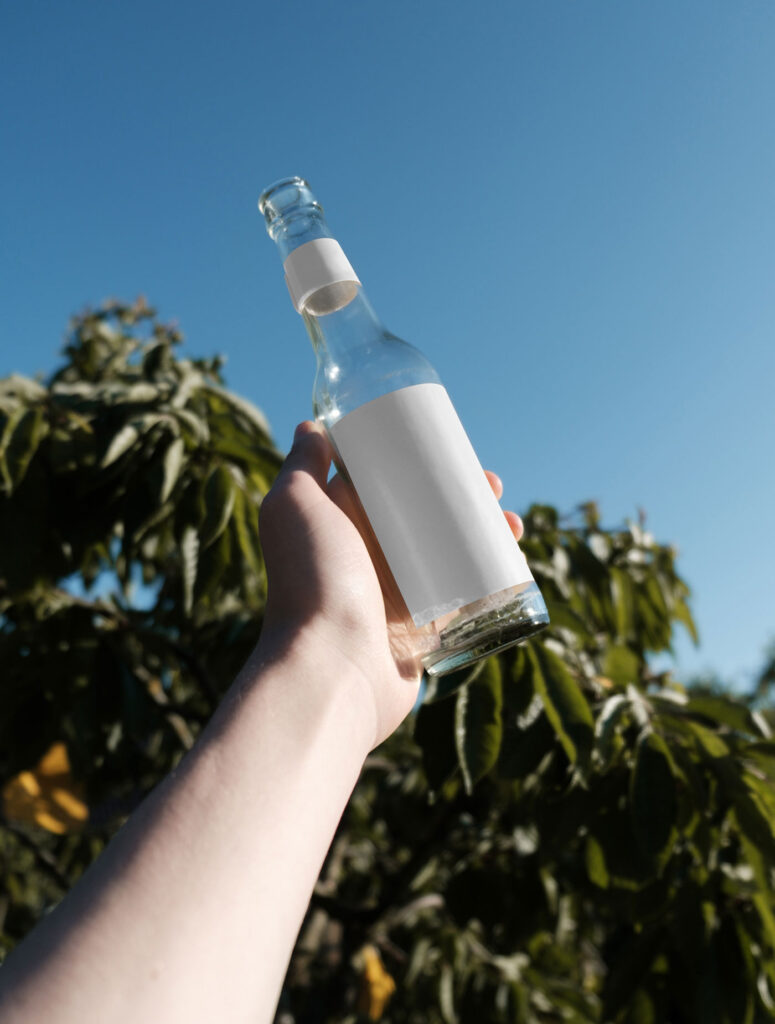 Handholding Glass Bottle Mockup in Nature