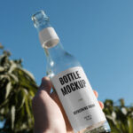Handholding Glass Bottle Mockup in Nature
