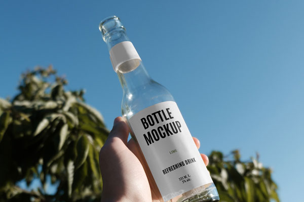 Handholding Glass Bottle Mockup in Nature