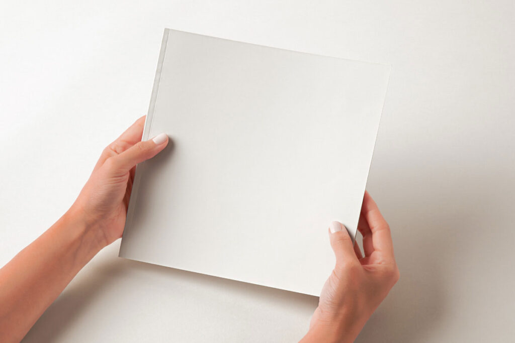 Hands Holding Square Catalog Mockup in Perspective View