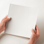 Hands Holding Square Catalog Mockup in Perspective View
