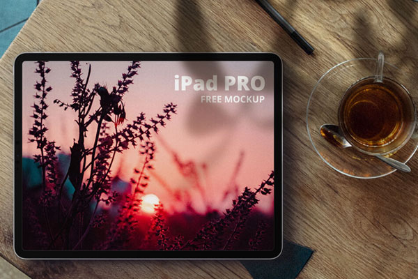 iPad Pro Next to a Cup of Tea on a Wooden Desk Mockup