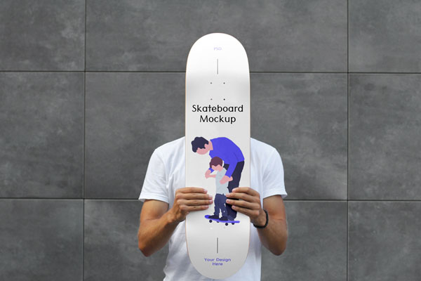 Man Holding Skateboard Mockup Against Brick Wall