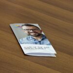 Mockup Displaying a Closed Flyer on a Wooden Table