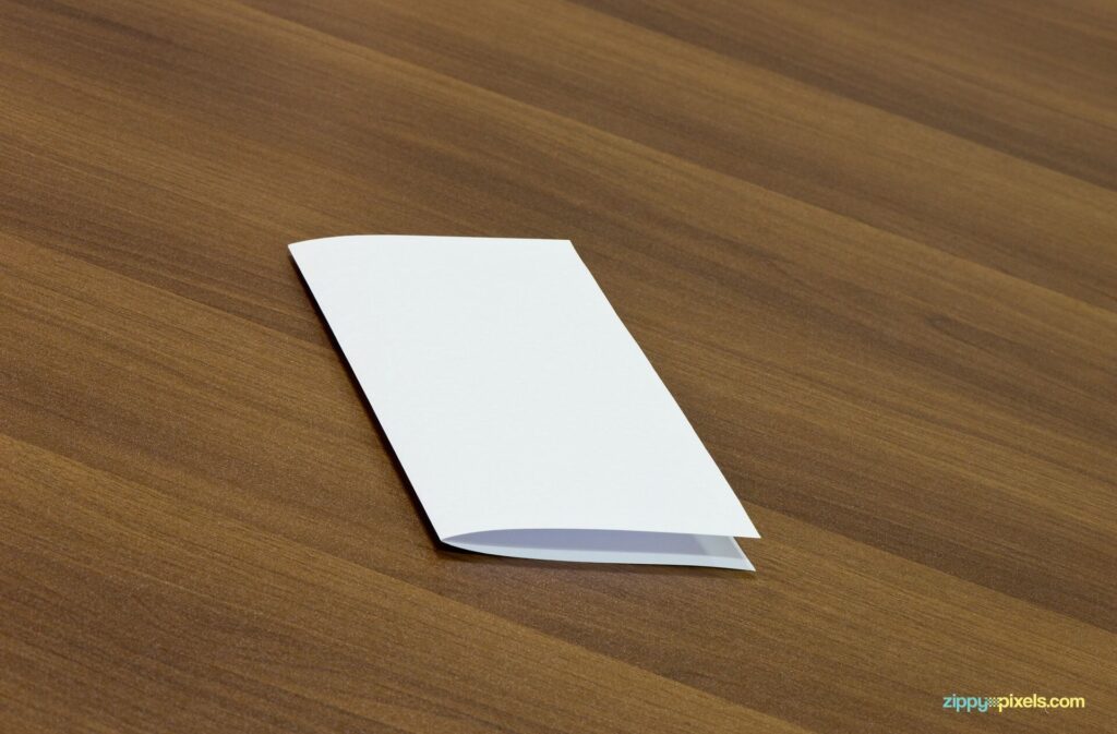 Mockup Displaying a Closed Flyer on a Wooden Table