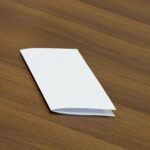 Mockup Displaying a Closed Flyer on a Wooden Table