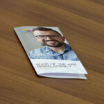 Mockup Displaying a Closed Flyer on a Wooden Table