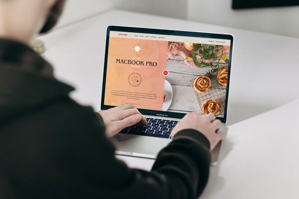 Mockup Featuring a Man Using MacBook Pro on a Table