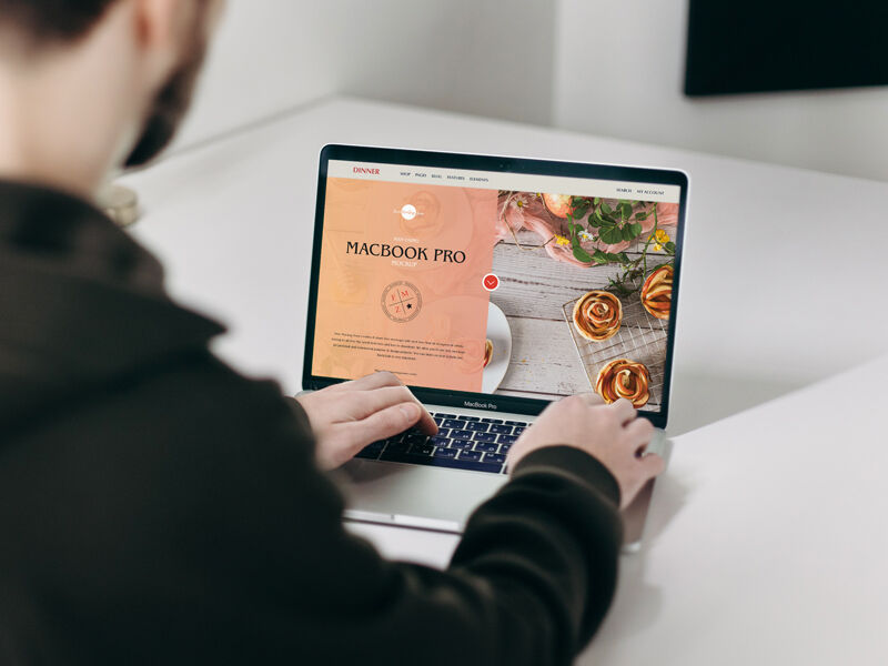 Mockup Featuring a Man Using MacBook Pro on a Table