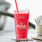 Mockup Featuring Big Glass of Juice on a Table at a Cafe