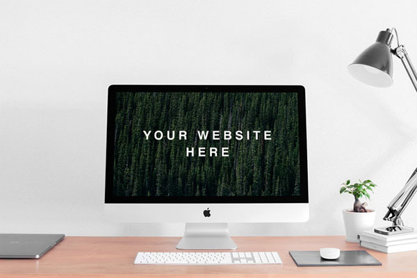 Mockup Featuring Realistic iMac on a Desk Next to a Lamp and a Plant