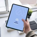 Mockup Showcasing Hand Holding iPad in a Office Table Scene