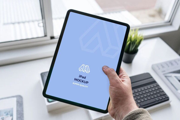 Mockup Showcasing Hand Holding iPad in a Office Table Scene