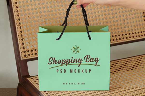 Mockup Showing a Hand Holding Shopping Bag on a Bench