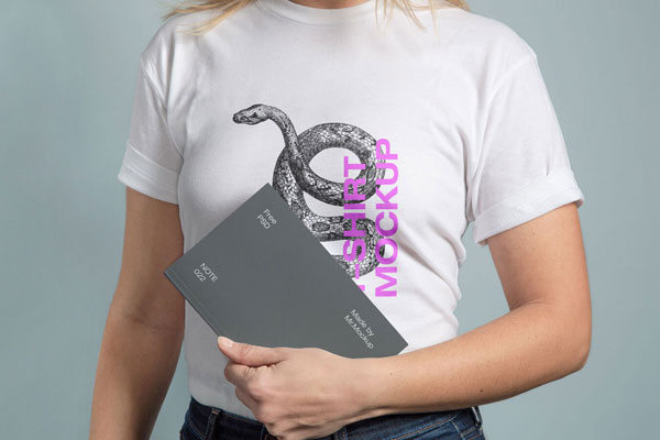 Mockup Showing a Woman Wearing T-Shirt and Holding a Notebook