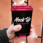 Paper Coffee Cup Held By Hand in the Front View Mockup