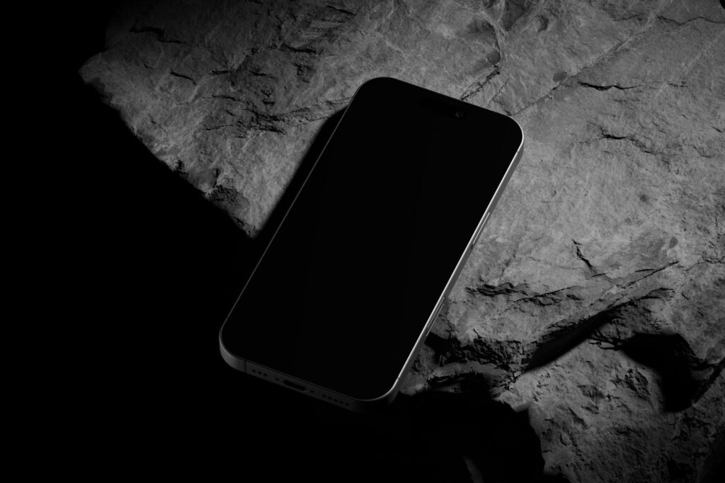 Perspective Vision of Black Titanium iPhone 16 Pro Mockup on Rock