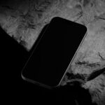 Perspective Vision of Black Titanium iPhone 16 Pro Mockup on Rock