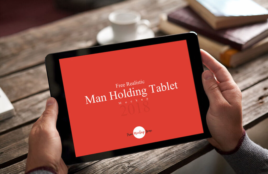 Realistic Man Holding Tablet on Wooden Table Mockup