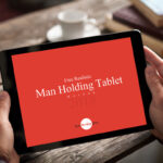 Realistic Man Holding Tablet on Wooden Table Mockup