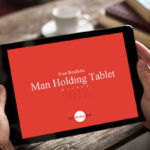 Realistic Man Holding Tablet on Wooden Table Mockup