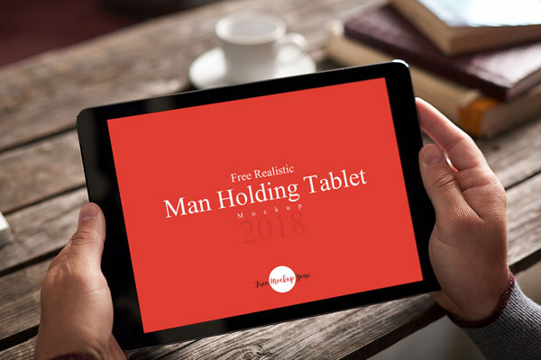 Realistic Man Holding Tablet on Wooden Table Mockup