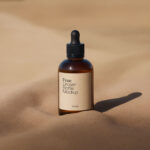 Amber Dropper Bottle Mockup with Sand Background