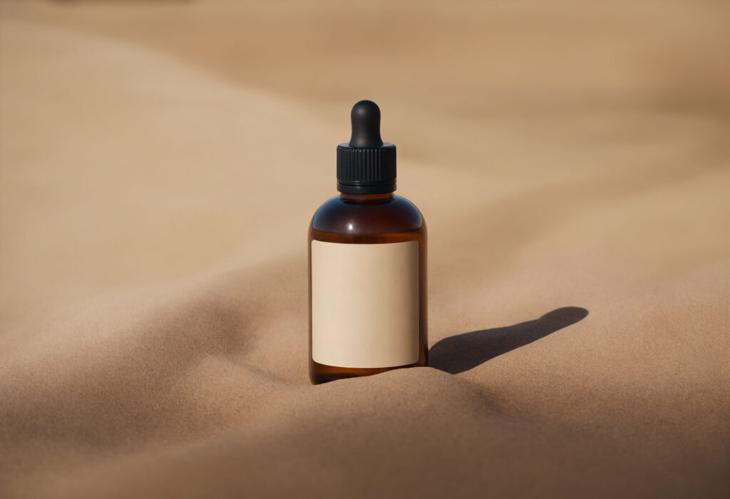 Amber Dropper Bottle Mockup with Sand Background