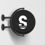 Round Signage Put up on the Wall in Half-Side View Mockup