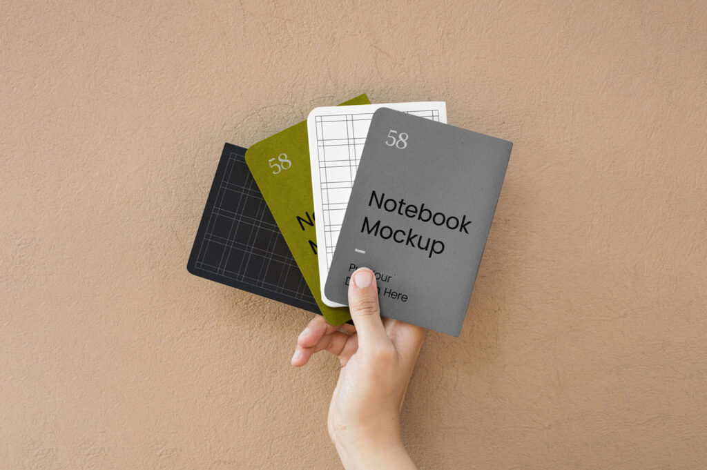 Top View of a Hand Holding Four A5 Notebook Cover Mockup